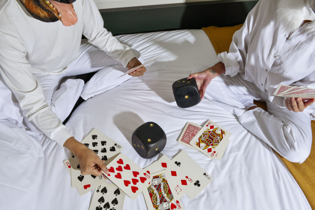People playing cards and dice on top of bed sheets