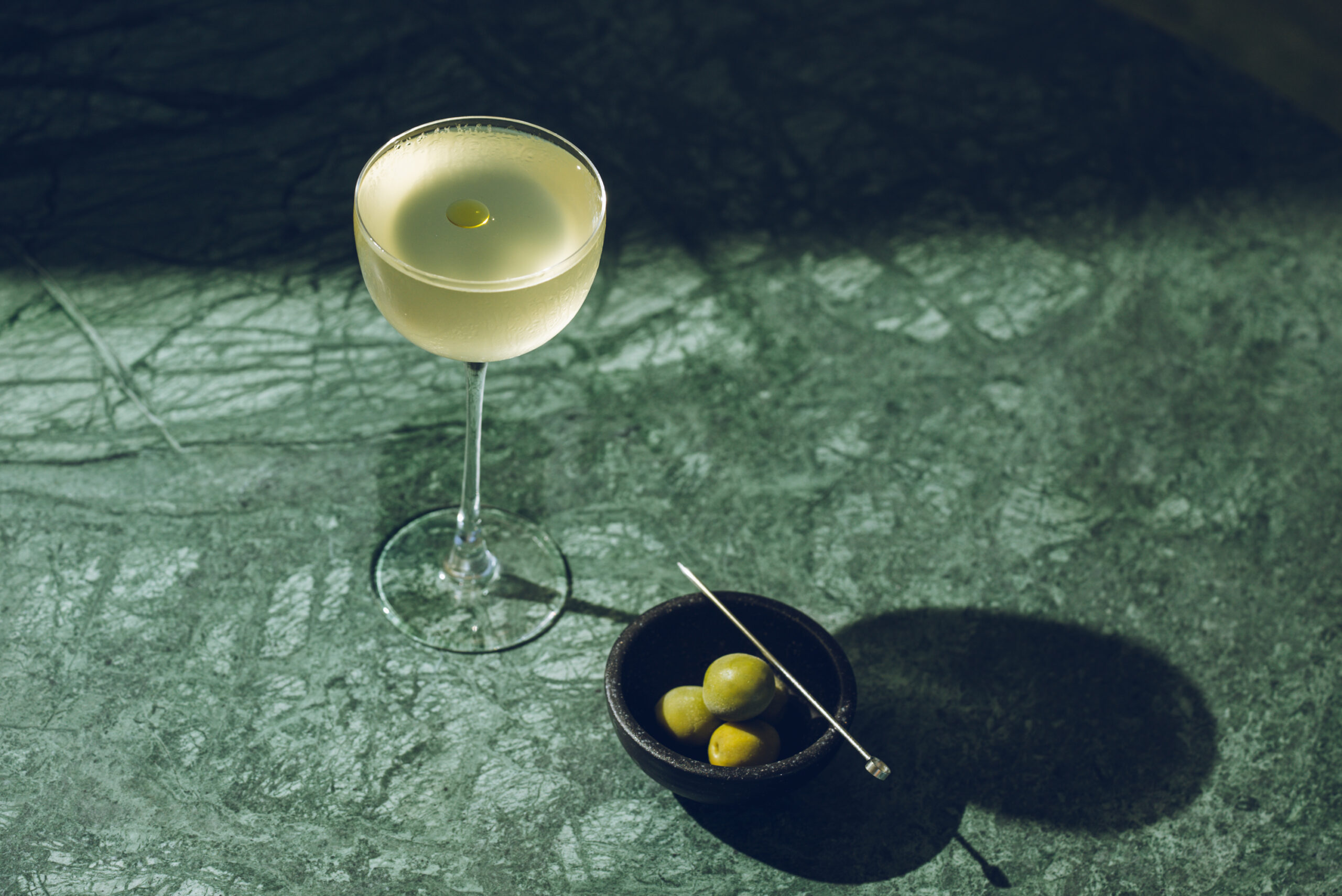 A glass of white wine with olives on a table, creating a delightful combination of flavors and colors.