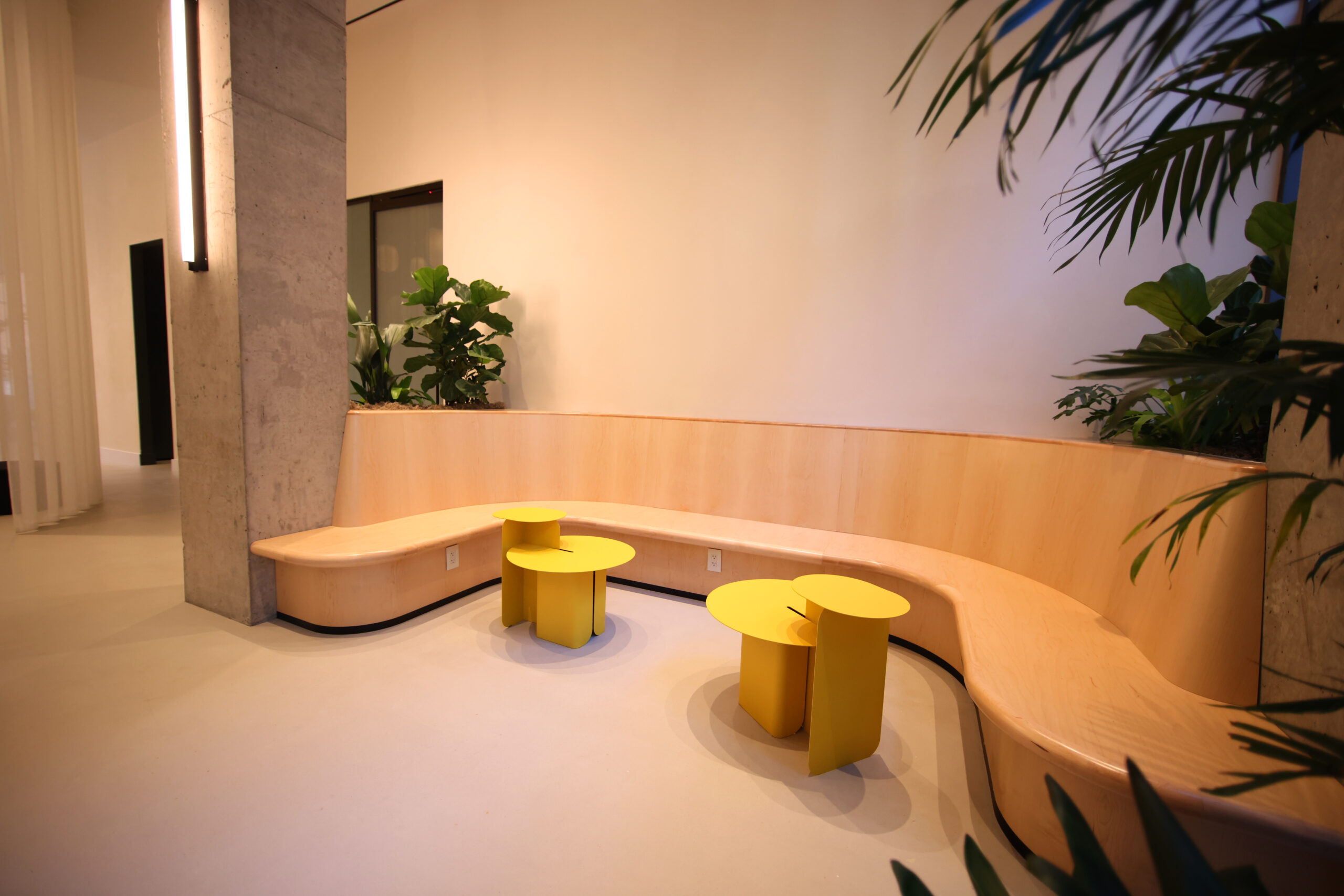 A wood table, plants and yellow seats